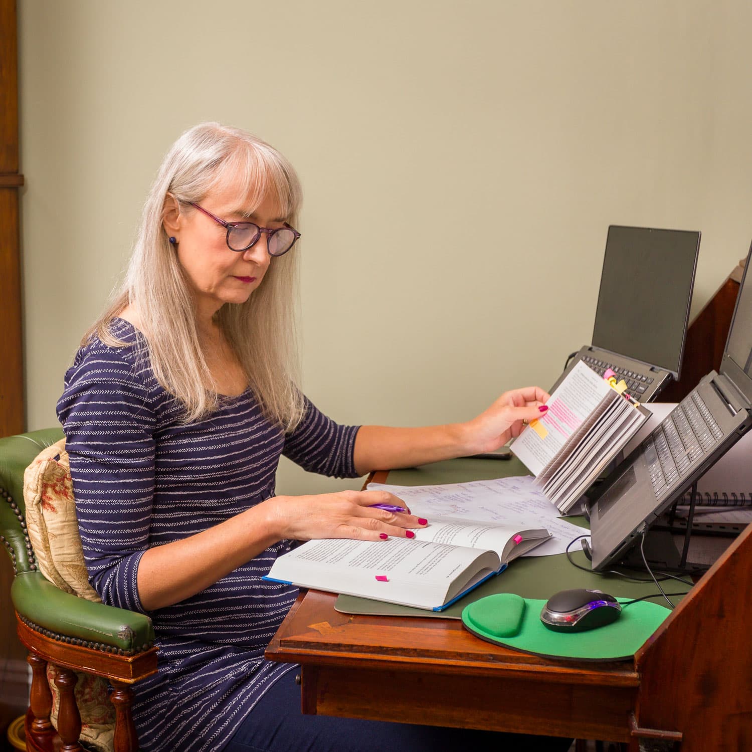 Melanie Cotton, proofreader and editor, gimlet-eyed grammar tickler® sitting at her desk, consulting hard copy resources while proofreading a document on her computer